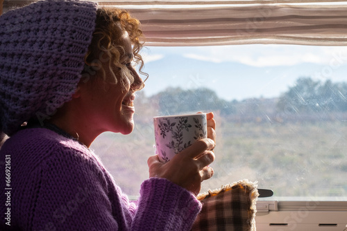 One woman side view smile and enjoy travel lifestyle and destination drinking coffee and admiring the view outside the widow of her camper van. Van life. Alternative vehicle travel vacation people photo