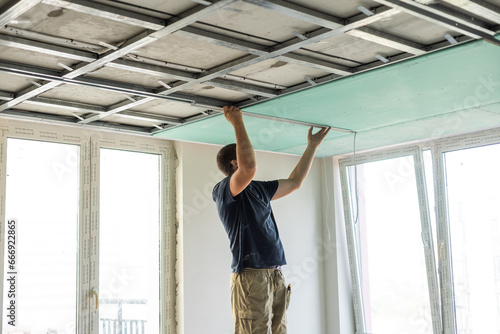 Canvas-taulu Man assembles profile metal frame for plasterboard ceilings