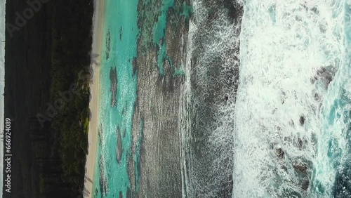 Aerial shot of waves breaking over reef on Yejele Beach, New Caledonia. Vertical format photo