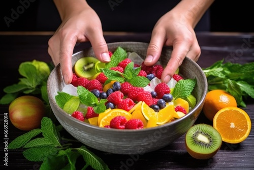 tossing a mint leaf into a bowl of mixed fruit