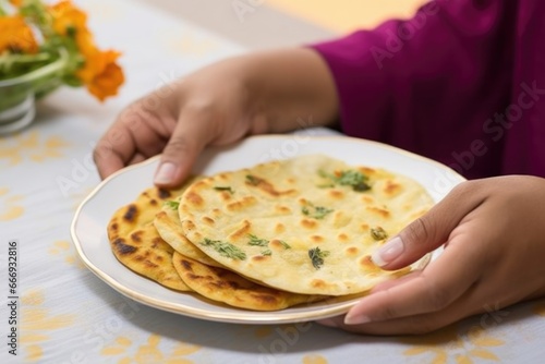 hand serving a piece of peshwari naan on a white plate photo