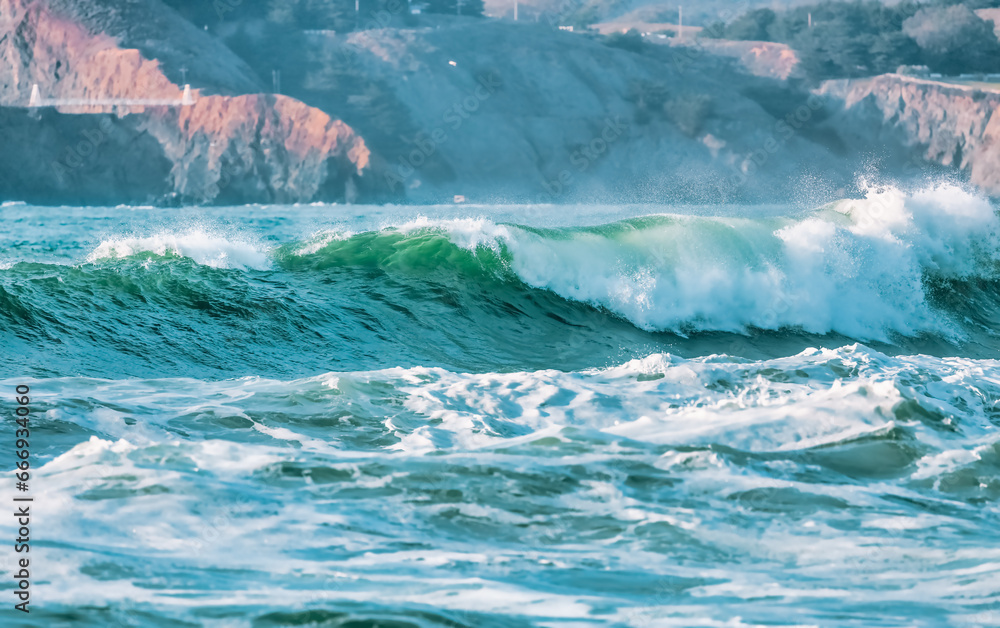 Wave splashes close-up. Crystal clear sea water hitting rock formations in the ocean in San Francisco Bay, blue water, pastel colors.