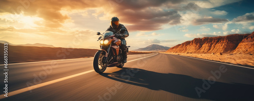 Driver riding motocycle on empty road in sunset light.  Panorama photo.