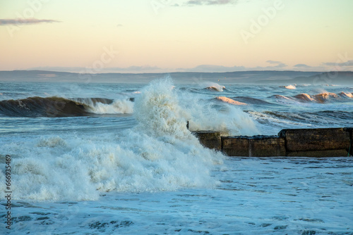 Slika na platnu Storm hitting the coast of Scotland with crashing waves coming over a harbour wa