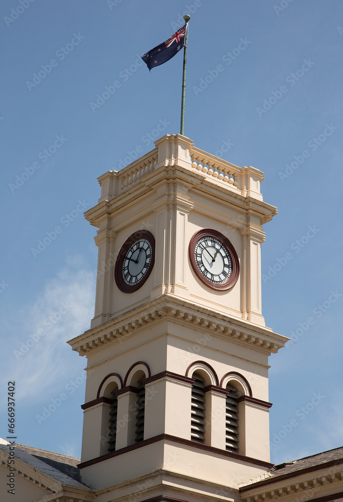Obraz premium Clock tower of the historic post office (built 1876-1877) flying the Australian flag in Maryborough, Victoria, Australia.