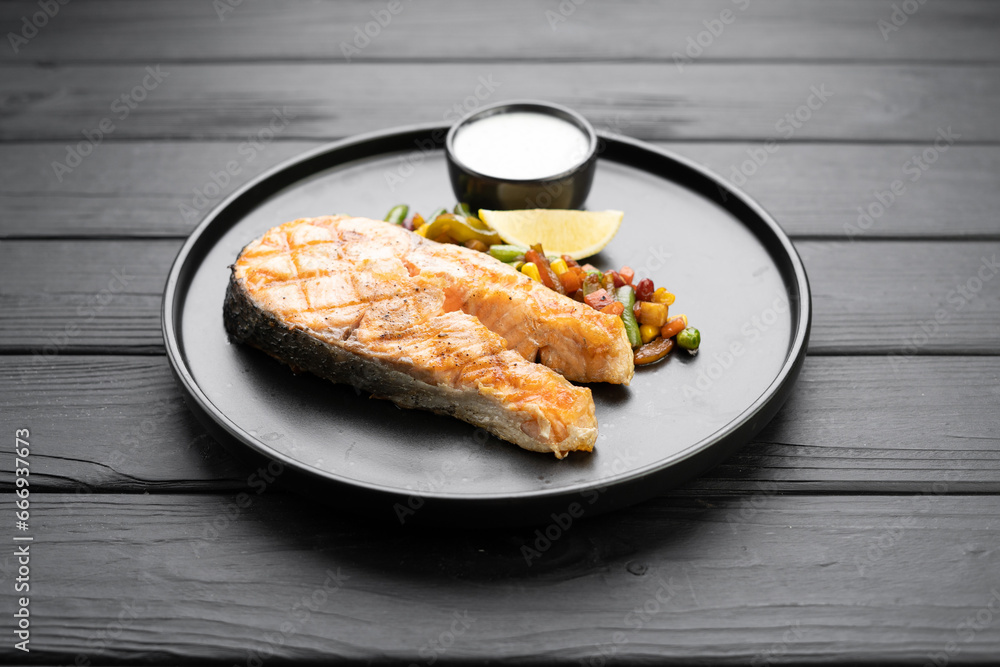 Grilled salmon steak with vegetables mix on black background, top view. Grilled salmon steak with vegetables mix on black background, top view.