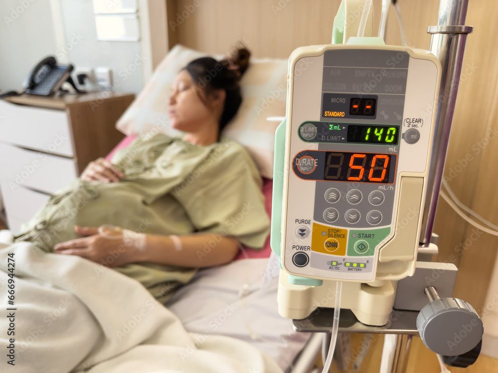 automatic infusion IV drip saline pump machine with pregnant woman resting on bed in hospital - obrazy, fototapety, plakaty 