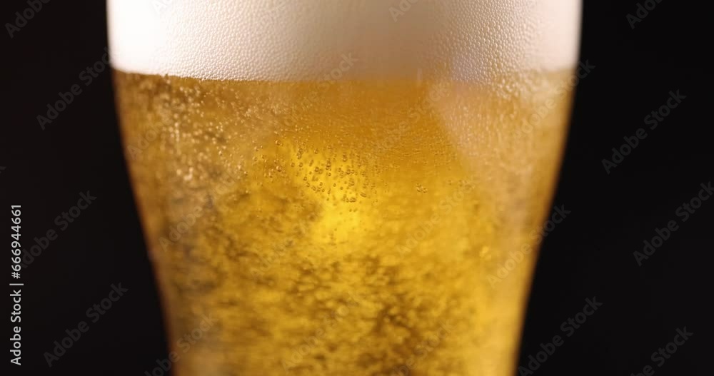 Golden beer pouring into glass with foam and many gas bubbles closeup 4k movie slow motion. Alcohol addiction concept Golden beer pouring into glass with foam and many gas bubbles closeup 4k movie slow motion. Alcohol addiction concept