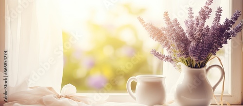 Lavender flowers in watering can and photo frame displayed on window with tulle cloth background with empty area Slightly blurred