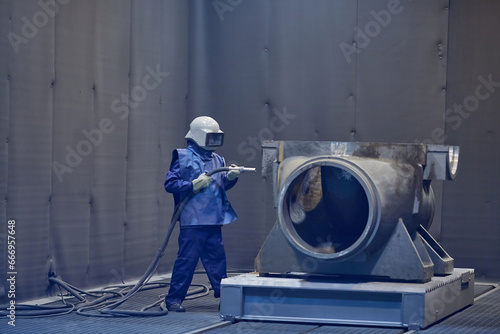 фотографія worker processes workpiece with sandblasting tool in factory, selective focus