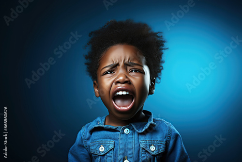 black child boy screaming crying on blue isolated background