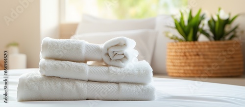 Clean towels stacked on bed in bedroom with a cozy double bed
