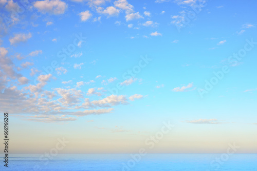 Sunrise sky across blue ocean to colours above distant horizon