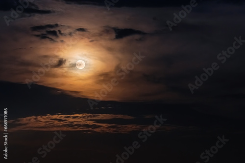 Full Moon surrounded by clouds in the night sky. Moonlight on a cloudy night