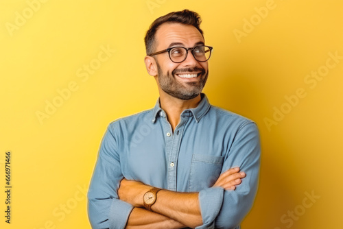 Portrait of handsome cheerful young businessman pointing at something. Professional young man in a suit on yellow background making hand gesture. photo