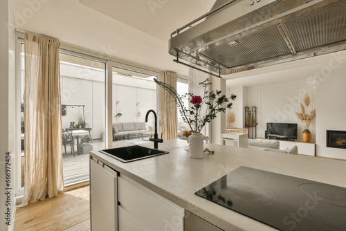 a kitchen and living room in a residential area with sliding glass doors that open onto the patio to an outdoor terrace