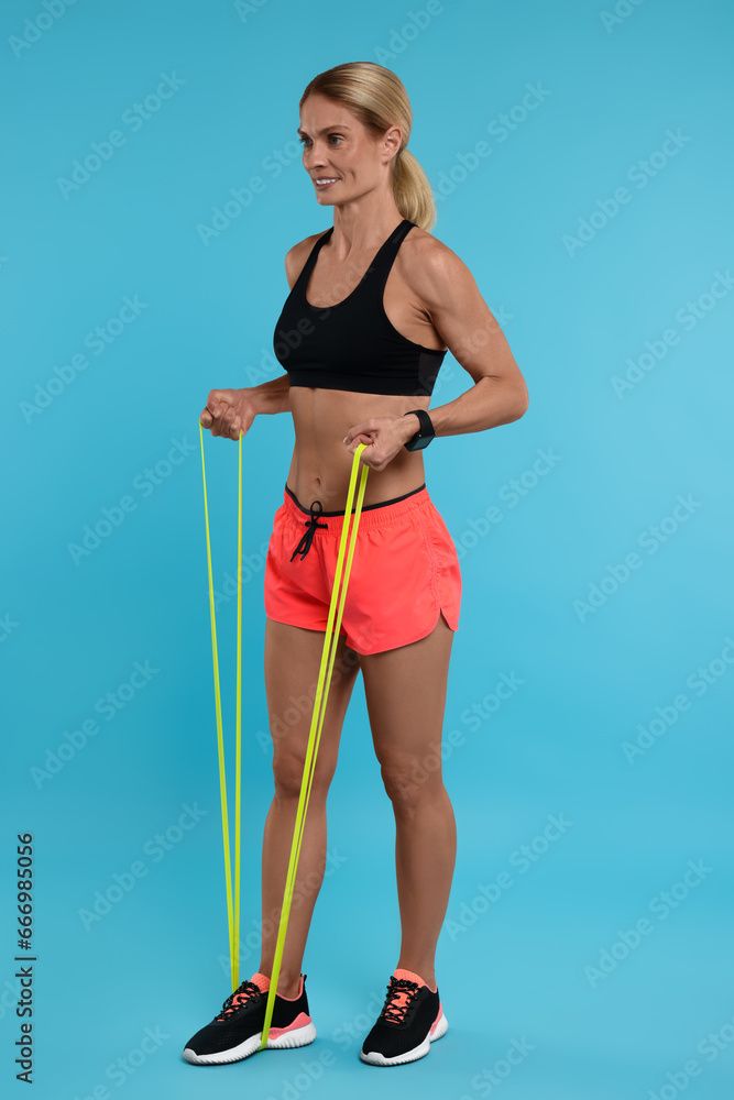 Woman exercising with elastic resistance band on light blue background Woman exercising with elastic resistance band on light blue background