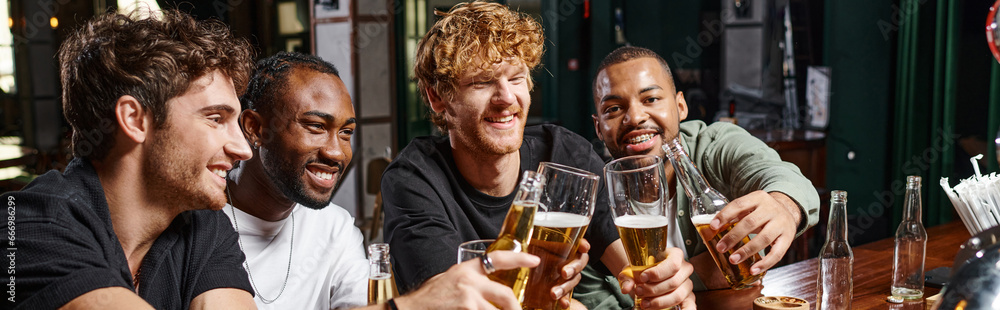 group of four happy multiethnic male friends toasting with glasses of beer at bar counter, banner group of four happy multiethnic male friends toasting with glasses of beer at bar counter, banner
