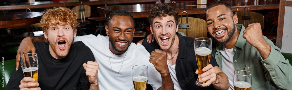 Φωτογραφία banner of excited interracial friends cheering with glasses of beer in bar, men