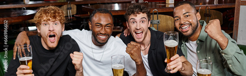 Canvas Print banner of excited interracial friends cheering with glasses of beer in bar, men