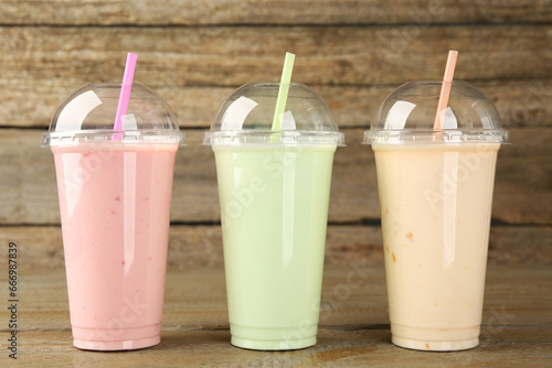 Plastic cups with different tasty smoothies on wooden table