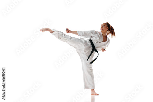Attractive woman in white sport karate uniform with black belt training in action against white studio background.