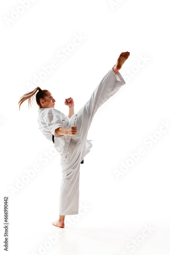 Rear view. Woman professional karate fighter performing kick in action isolated over white background.