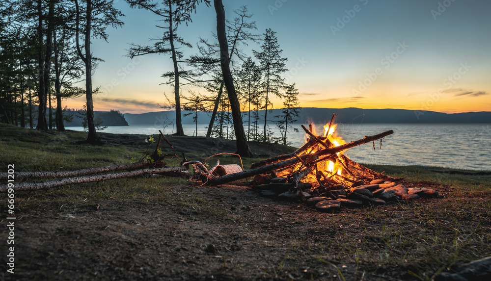 The flame of a bonfire on the background of the evening summer lake Baikal. Hiking trips to unique places of nature