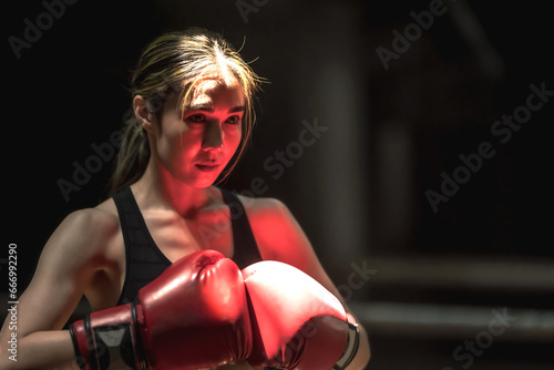 Confident Muay Thai boxer woman with boxing gloves ready to fight, copy space