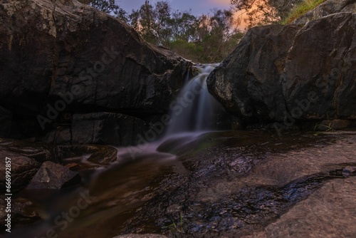 Scenic view of a cascading waterfall surrounded by jagged rocks and lush greenery