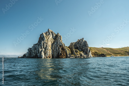 Shamanka Rock on Olkhon island of Lake Baikal. Summer landscape with reflection in the water on a clear sunny day. Unique places of Siberia photo