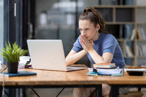 Portrait of tired young business Canada woman work with documents tax laptop computer in office. Sad, unhappy, Worried, Depression, or employee life stress concept