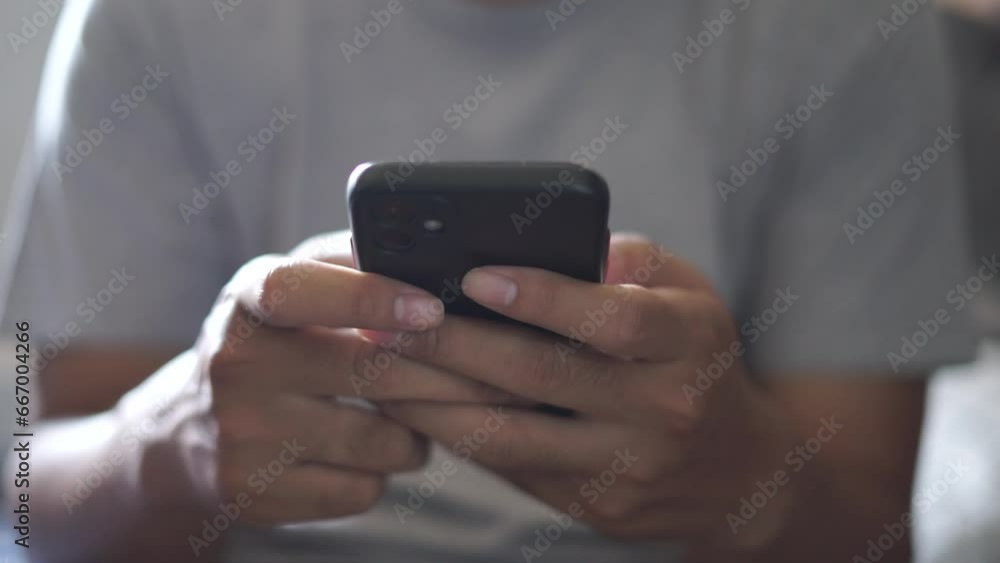 Hands of Asian man holding checking touching scrolling smartphone from bed room Hands of Asian man holding checking touching scrolling smartphone from bed room