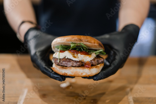 manos sujetando una burger con queso brie y mermelada