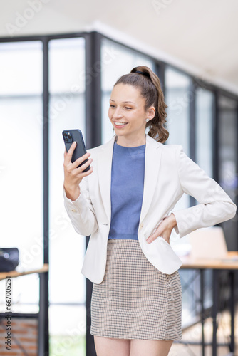 Smiling business canada woman standing and using her phone in the office. 