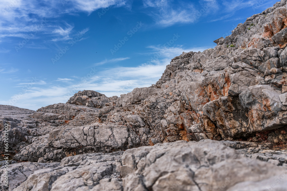 Gray stone rocks against a blue sky with clouds, nature background Gray stone rocks against a blue sky with clouds, nature background