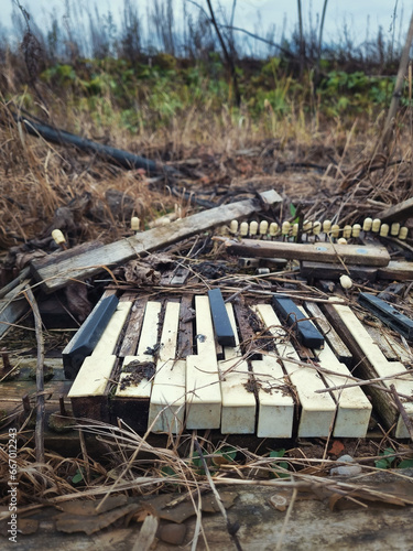 A broken sad piano in the grass in autumn 