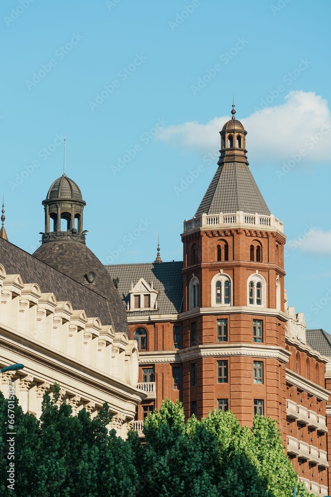 the view of a large brick building from the ground with trees and bushes surrounding it