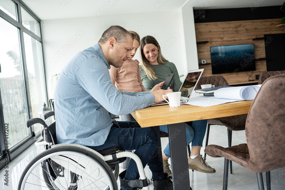 A physically challenged father works from home, supported by his family, who find moments of joy and connection amidst their daily routine. A physically challenged father works from home, supported by his family, who find moments of joy and connection amidst their daily routine.