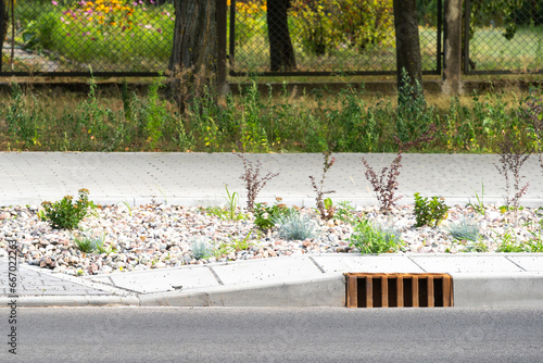 Fotografie Metal grid of water gutter system in stone curb at roadside