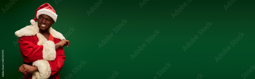 smiling charismatic african american man in christmas costume looking away on green backdrop, banner smiling charismatic african american man in christmas costume looking away on green backdrop, banner