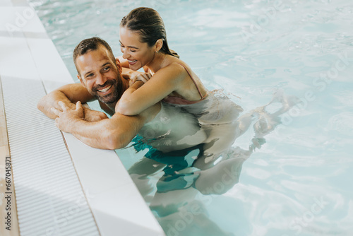 Bild auf Leinwand Young couple relaxing in the indoor swimming pool