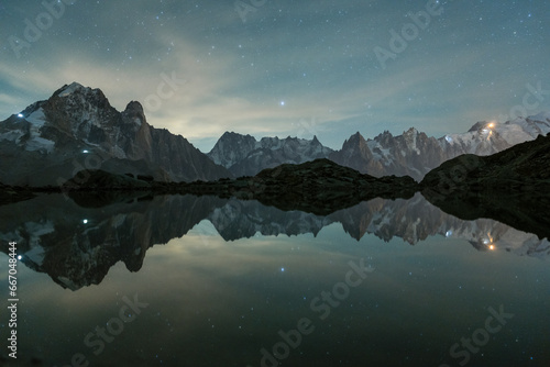 Starry Sky over Mountains and Reflection in Lac Blanc Lake. Night Landscape. Aiguilles Rouges, French Alps, France.