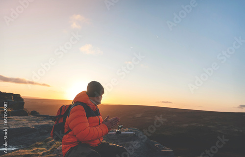 mature man hiking in mountain to take timelaps of sunrise, exercise and fitness for wellness, healthy lifestyle and smile. senior mature gentleman sitting on rock, enjoing calm day toned image