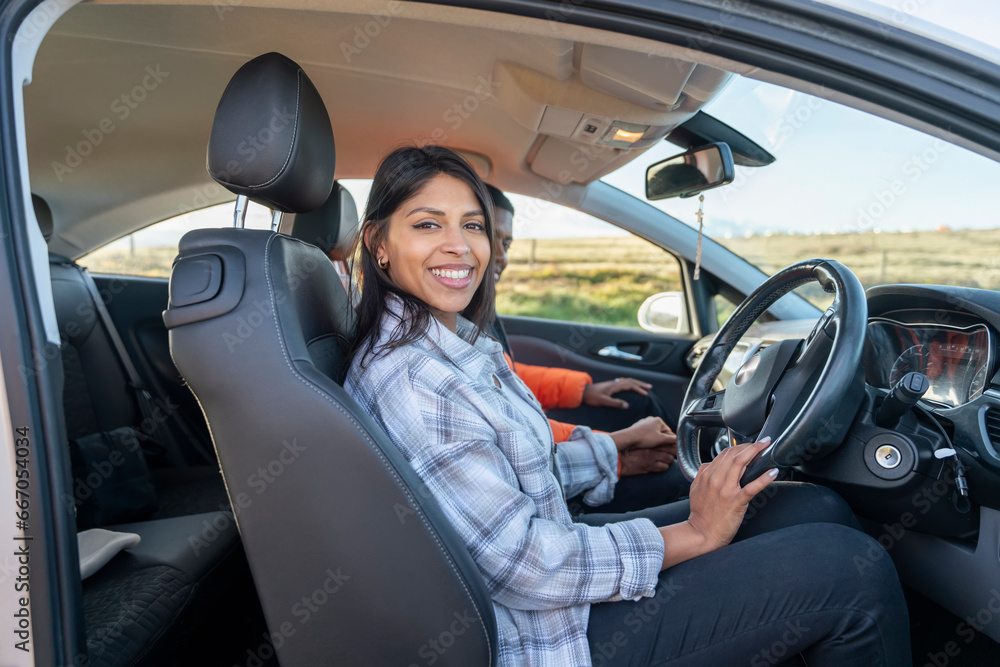 Portrait of a young woman sitting in a car and  holding on to the steering wheel. Buy your first car concept