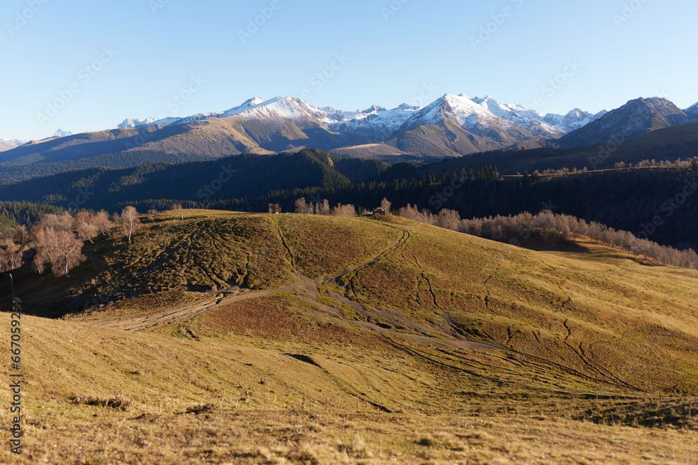Autumn landscape of the nature of the mountains on a trip with snow-capped winter peaks in the background, off roads