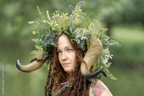 A pretty young faun in the woods. Mythological forest creature at the tree photo