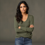 annoyed poc woman standing with folded arms, isolated on plain olive green studio background