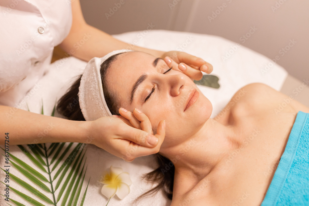 Naklejka premium Beautiful woman in spa salon getting face massage treatment. Girl facial treatment. Skin care. Body care.