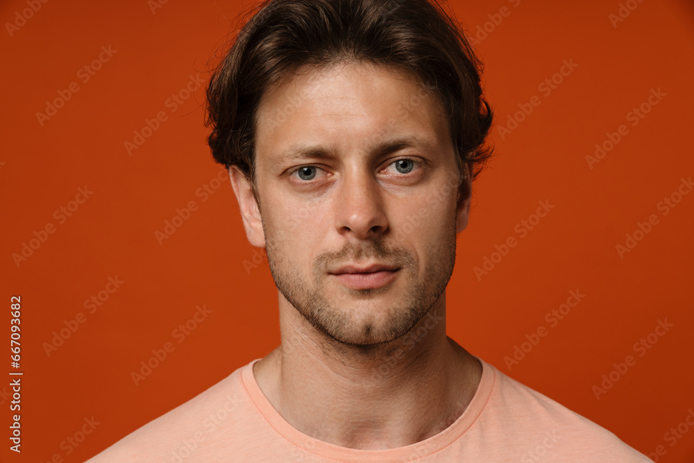 Young man looking at camera while standing isolated over red background Young man looking at camera while standing isolated over red background